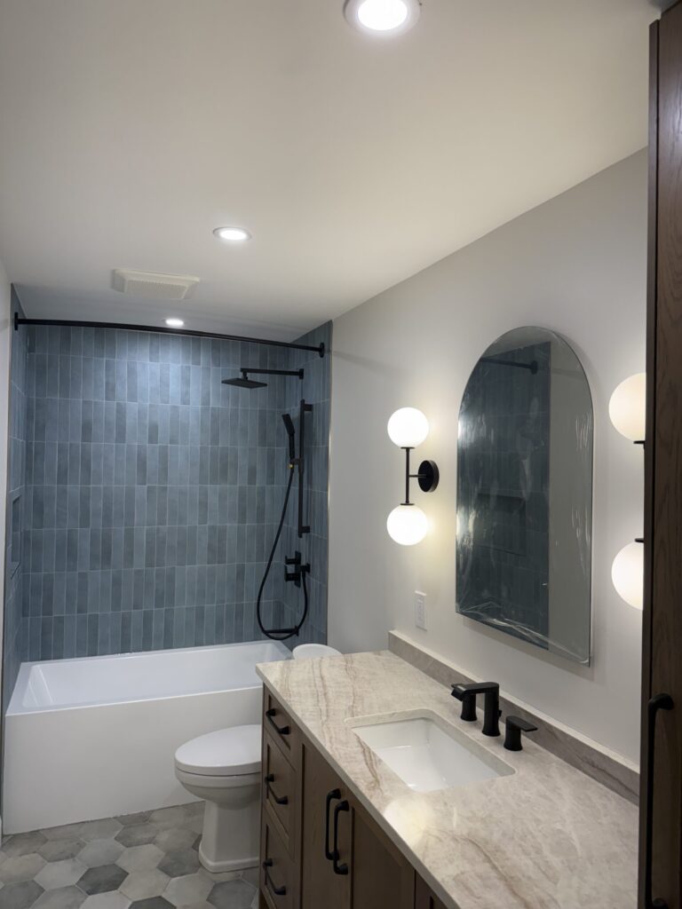 Bathroom with an arched mirror, globe wall sconces and pot lights