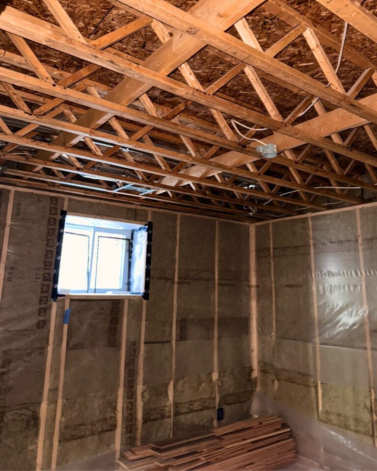 Basement renovation at electrical rough-in, with open ceiling and framed walls