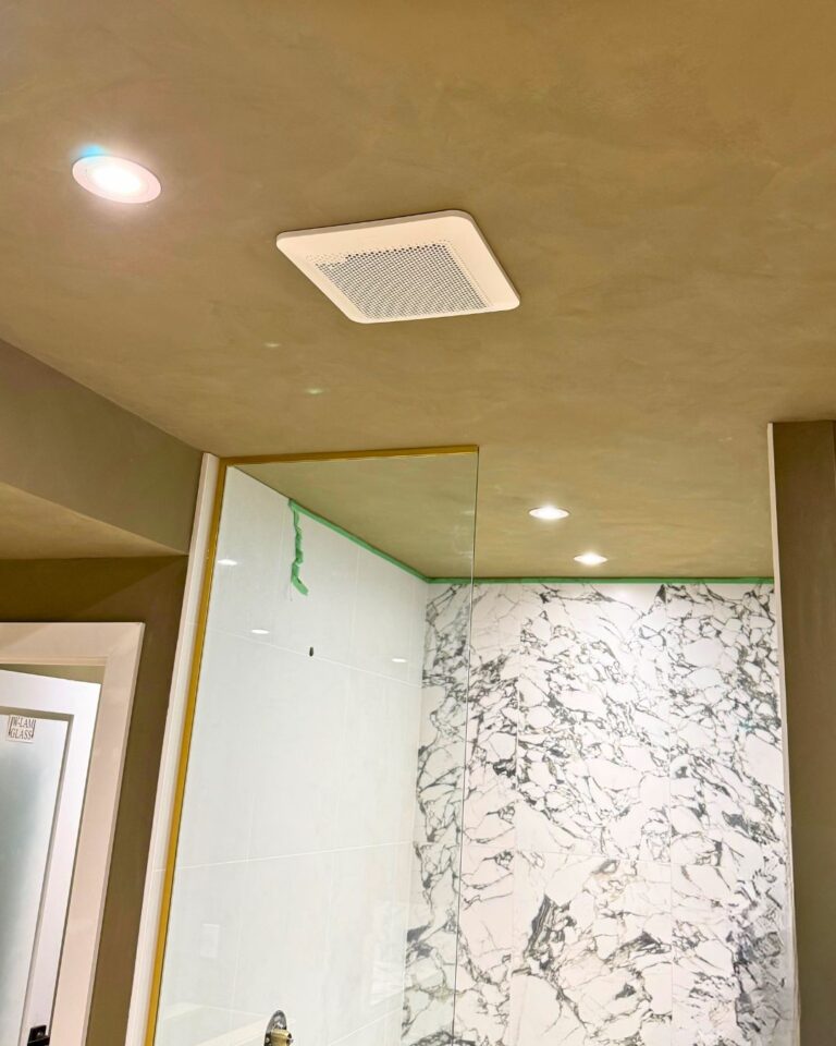 Finished bathroom with ceiling fan, pot lights and a marble shower wall