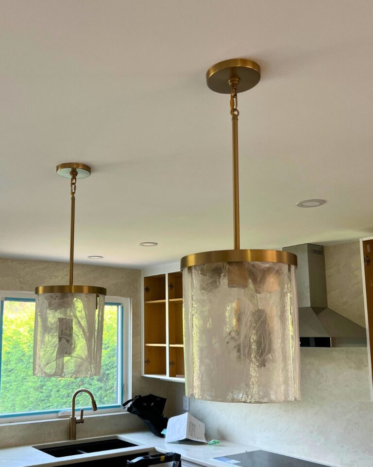 Brass and glass pendant lights installed over a kitchen sink