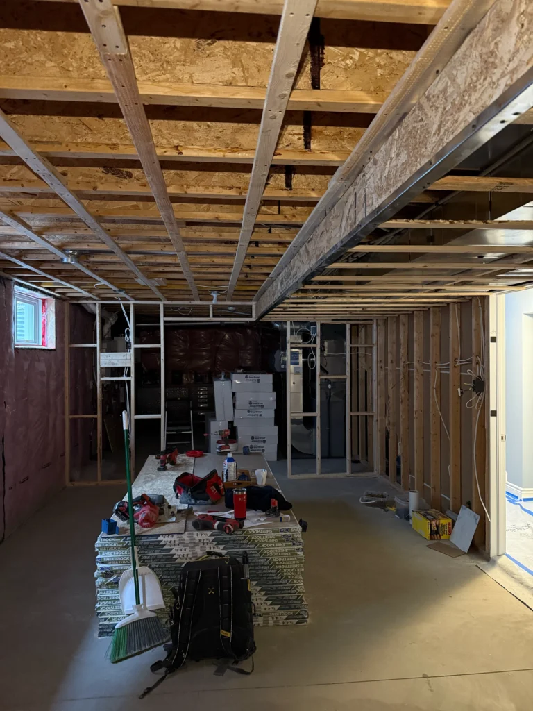Basement in Stittsville during electrical rough-in, with exposed ceiling joists, wall framing and wiring.