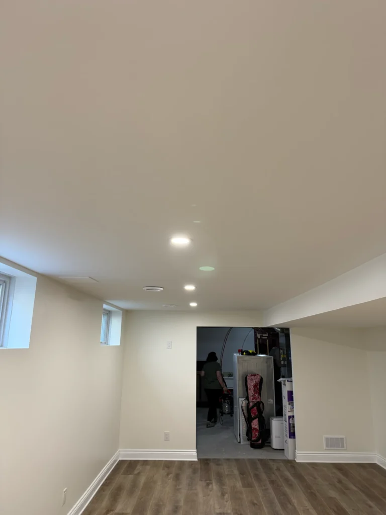 Basement in Stittsville with recessed ceiling lights, small windows and an open utility area.